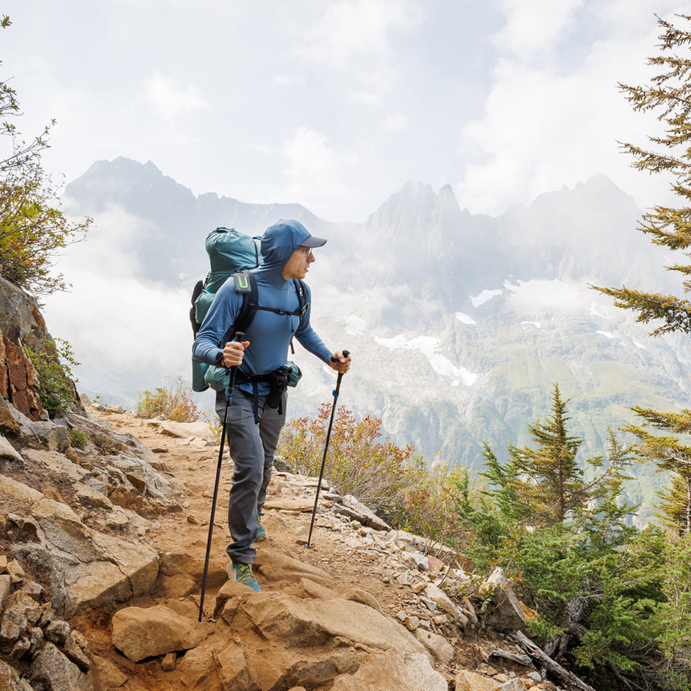 male hiker with blue sun hoodie enjoying view from high mountain trail