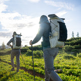 side view of backpackers wearing CS40 Ultra while hiking through green meadow