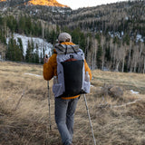 Rear view of hiker wearing Carbon Evo 50 backpack while hiking through open alpine terrain