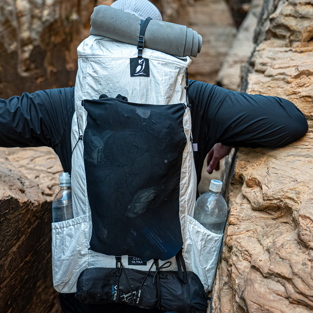 close rear view of CS40 Ultra Backpack on hiker as it brushes against sandstone walls