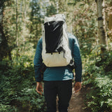 rear view of man hiking away through forest while wearing an ultralight backpack
