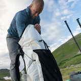 side view of man putting gear in ultralight backpack