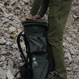 side view of men's green hiking pants in rocky peak environment
