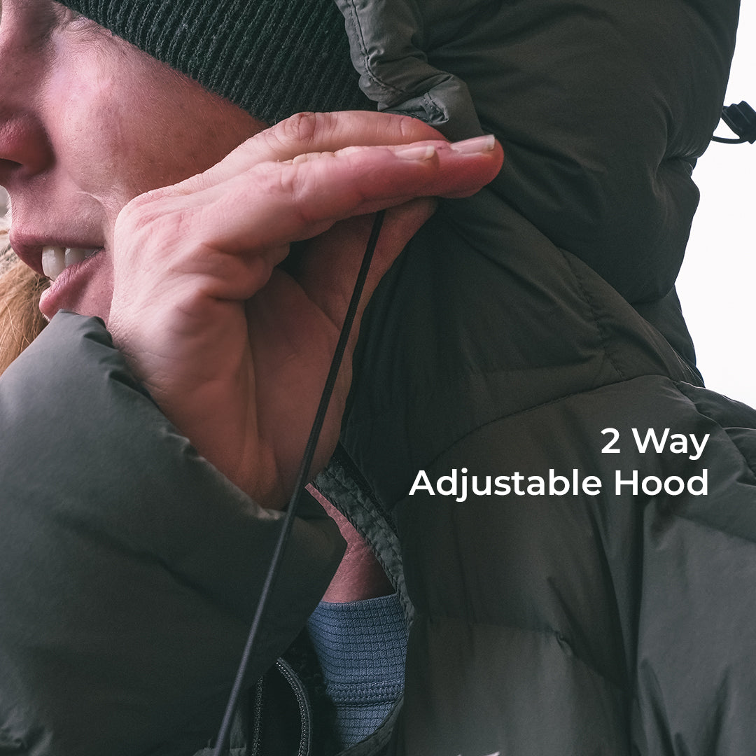 Close-up of a person wearing a dark puffer jacket with an adjustable hood, pulling the hood cord to demonstrate the 2-way adjustment, with white text overlay reading '2 Way Adjustable Hood'.