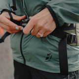 Close-up of Nebo Windbreaker with backpack strap, Nebo Windbreaker worn with backpack harness, Nebo Windbreaker waist and logo close-up