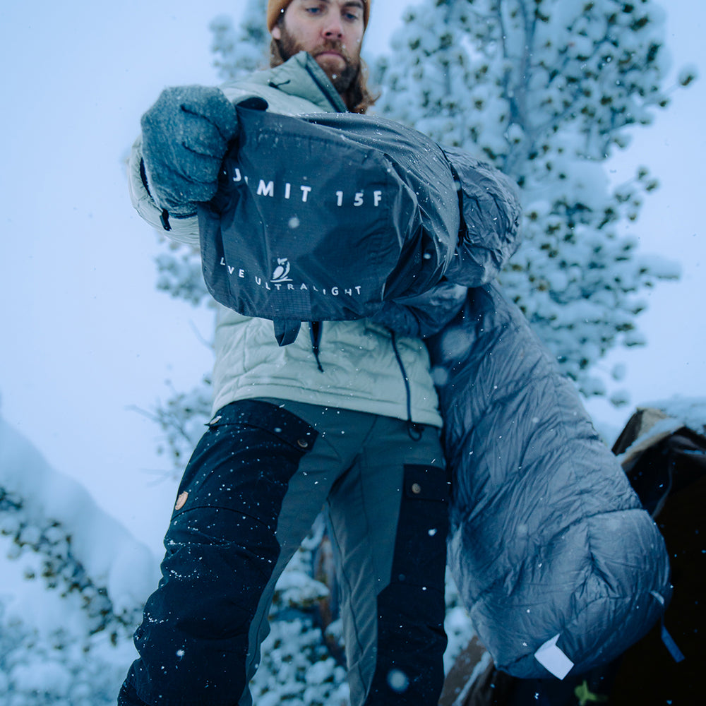 front view of man pulling sleeping bag out near his tent