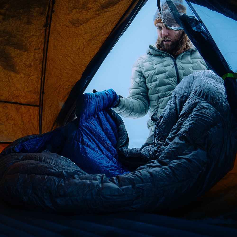 front view of man placing ultralight sleeping bag inside tent
