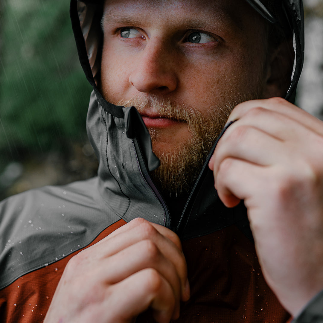 man zipping up rain jacket during storm