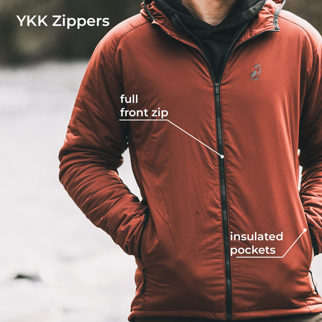 A person wearing a YKK zippers jacket with black zippers, shown from the chest down against a blurred outdoor background. White text overlays point out the full front zip and insulated pockets.