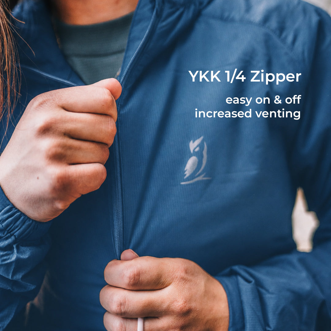 Close-up of a person wearing a blue lightweight jacket and pulling the zipper with both hands. White text on the right reads 'YKK 1/4 Zipper' and 'easy on & off increased venting'.