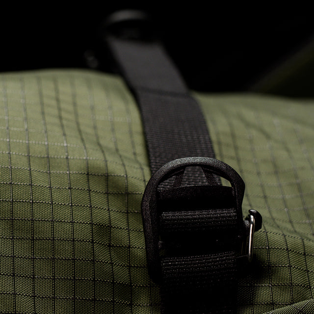Close-up of a green textured bag with a black strap and buckle.