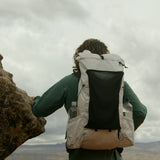 rear view of man wearing CS40 Ultra Backpack standing next to jagged stone