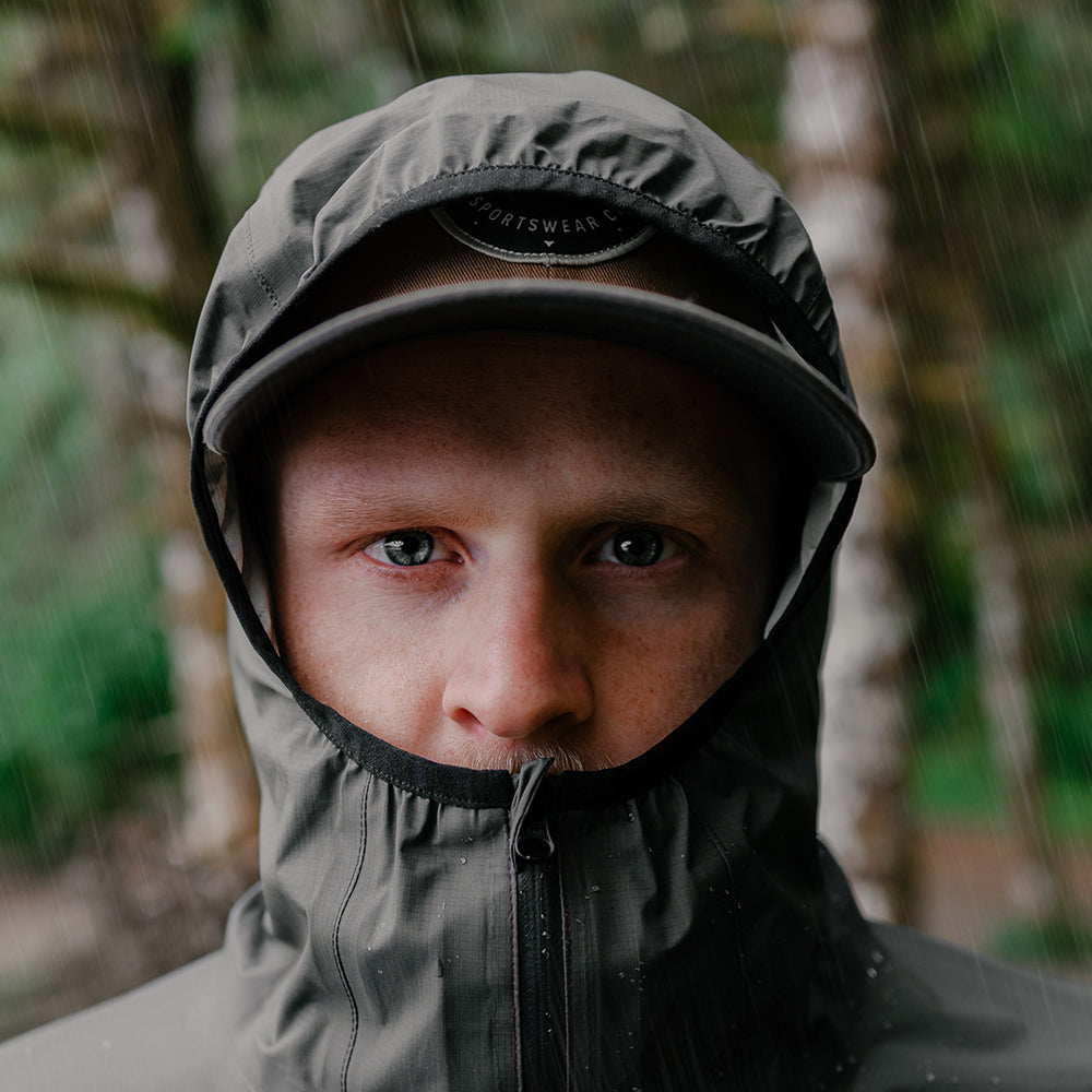 close front view of men's rain jacket hood up & high neck collar during rain storm