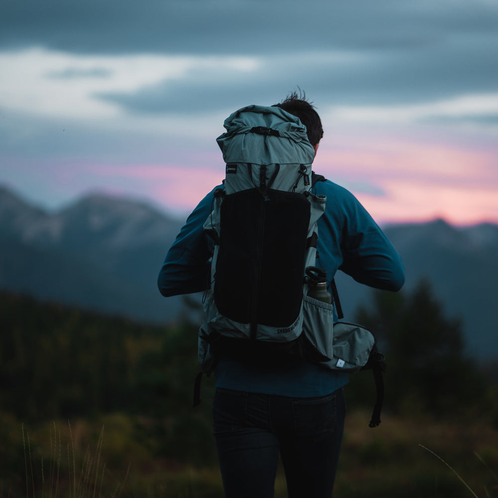 Adventurer in front of a mountain vista wearing the Shadowlight Ultralight Backpack