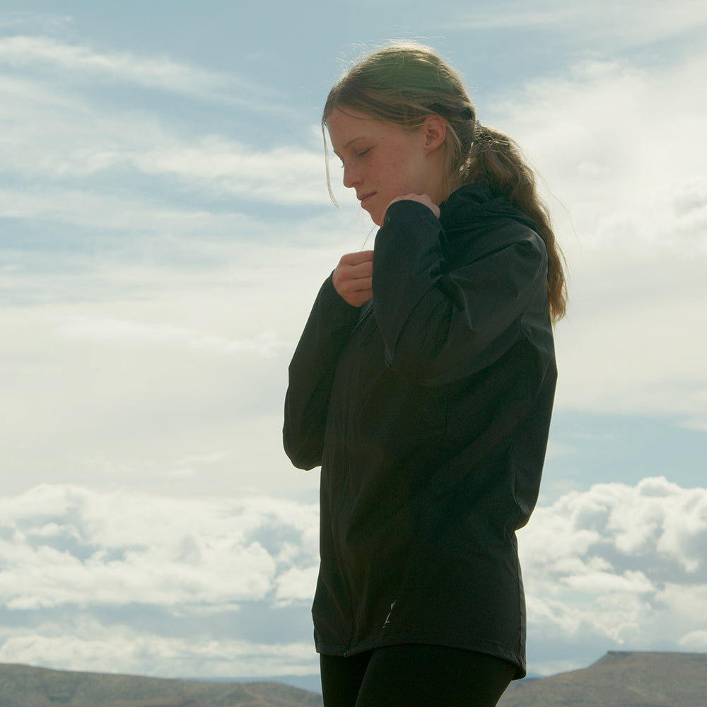 Woman wearing black Nebo Windbreaker outdoors under cloudy sky