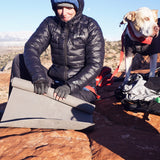 front view as woman rolls up closed cell foam sleeping pad outdoors