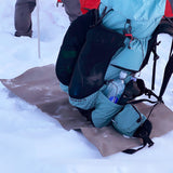 closed cell foam pad is laid out on top of snow with backpack on top of it