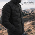 A man wearing a black 15 oz puffer jacket in an outdoor mountain landscape, with text overlay reading '15 oz Weight High Altitude Warmth'.