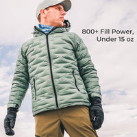 A man wearing a sage green quilted puffer jacket, black gloves, and a gray cap, set against a cloudy sky background with text that reads '800+ Fill Power, Under 15 oz'.