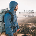A man wearing a blue hooded technical jacket and a large gray hiking backpack stands outdoors on a mountain ridge with a scenic forest valley in the background. Text on the right reads: '9 oz Weight 3 Season Warmth packs to the size of a grapefruit'.
