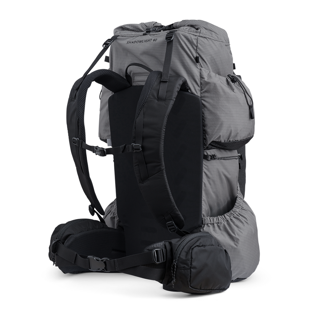 Side and rear angled view of the Shadowlight 60 ultralight backpack in gray, showing shoulder straps, hip belt, and large storage pockets.