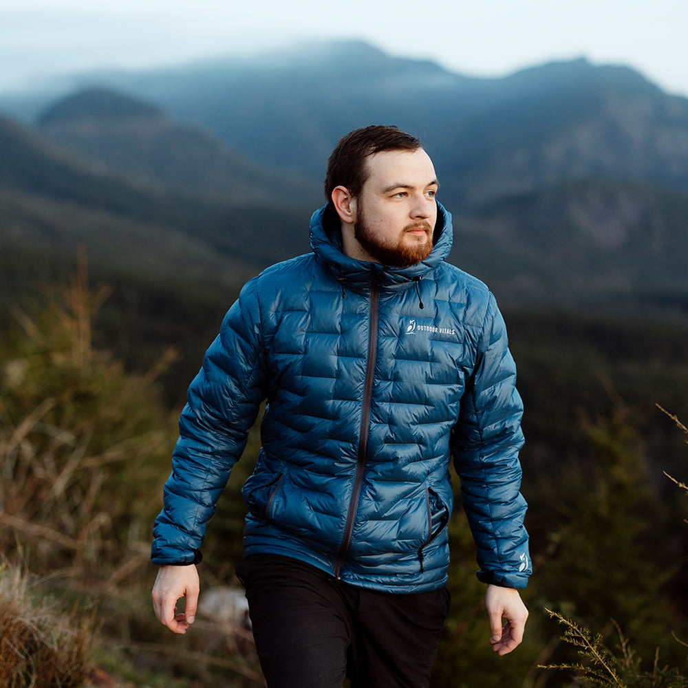 front view of man hiking uphill & wearing ultralight puffy jacket