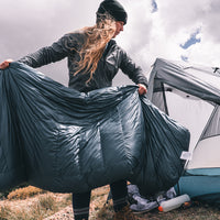 woman prepares backpacking sleeping bag before putting it inside her tent to camp.