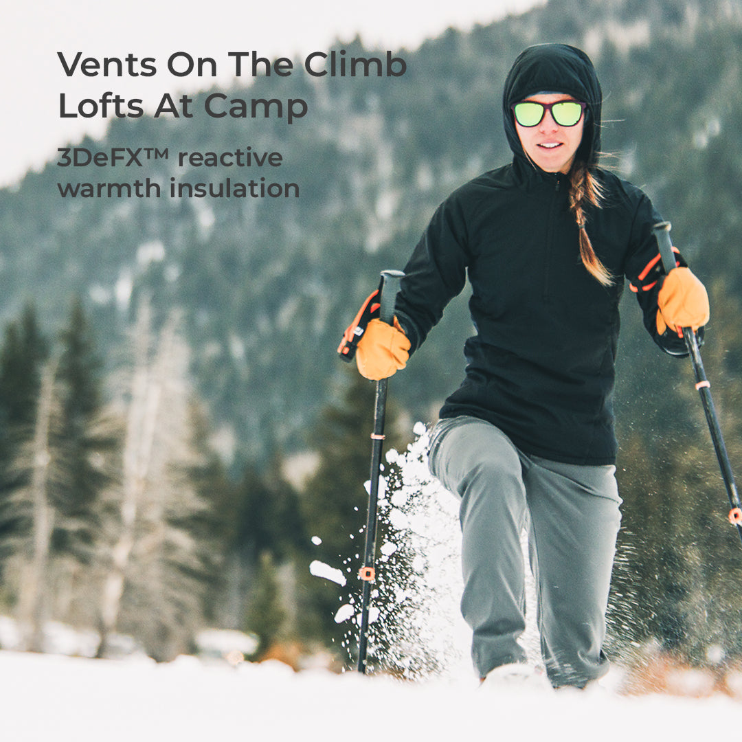A woman skiing in the snow wearing a black hooded jacket, gray pants, and orange gloves, with text overlay reading 'Vents On The Climb Lofts At Camp' and '3DeFX™ reactive warmth insulation'.