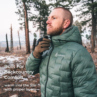 A man wearing an olive green puffer jacket and brown gloves stands in a forest, looking off-camera. White text on the left reads 'Built For Backcountry Comfort' and 'warm into the 30s with proper layers.
