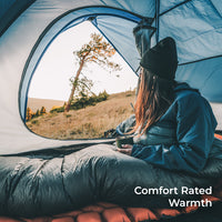 hiker sits inside red 30 degree quilt in tent looking out the door. Callout text says, "Comfort Rated Warmth."