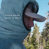 Side profile of insulated down jacket with fitted hood cinched around the face, designed to seal in heat in cold conditions.