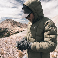 man wearing Vantage Alpine Down Jacket in high mountain setting while putting on gloves