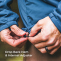 Close-up of a person's hands adjusting the hem of a blue jacket, demonstrating how to use the internal adjuster and drop back hem feature. White text at the bottom reads 'Drop Back Hem & Internal Adjuster'.