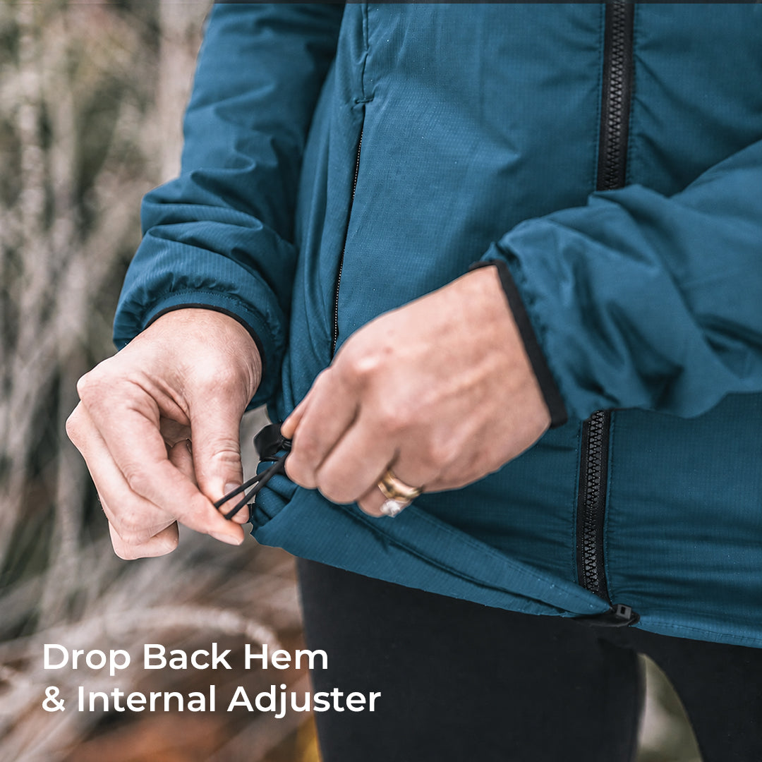 Close-up of a person outdoors adjusting the hem of a teal-blue jacket, with text reading 'Drop Back Hem & Internal Adjuster'.