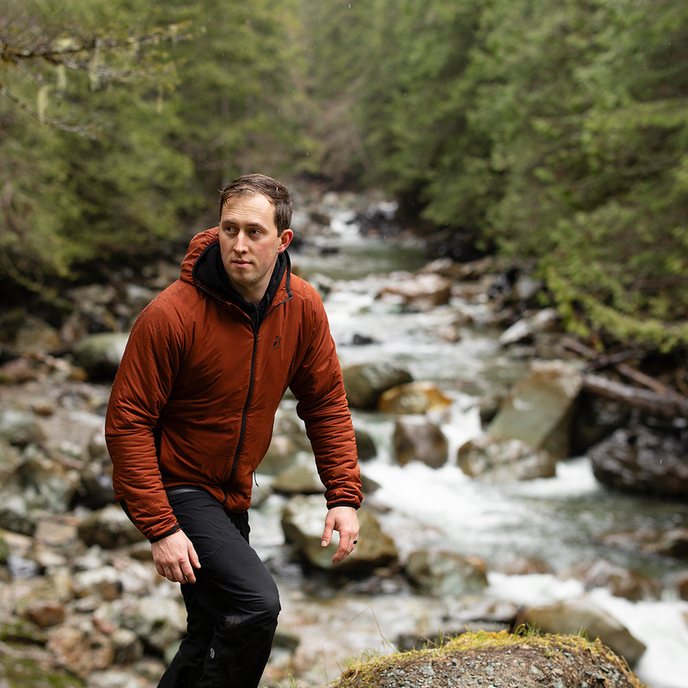 front view of man hiking with red ultralight full zipper jacket near river