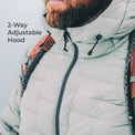 Close-up of a person wearing a light gray puffer jacket with a high hood and black zipper, with the text '2-Way Adjustable Hood' on the left. The jacket has a subtle 'DUNNOOR VITAL' logo on the chest.