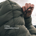 Close-up of a person wearing an olive green puffer jacket with a drawstring hood, showing a hand adjusting the hood. White text on the image reads '2-Way Adjustable Hood'.