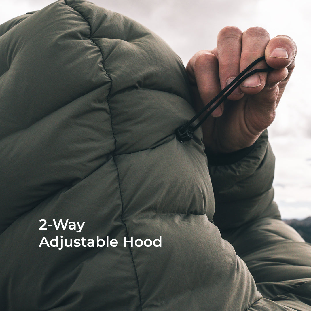 Close-up of a person wearing an olive green puffer jacket with a drawstring hood, showing a hand adjusting the hood. White text on the image reads '2-Way Adjustable Hood'.