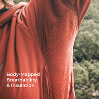 Close-up of a terracotta-colored hooded jacket with a body-mapped perforated ventilation panel, worn outdoors with trees in the background and the text 'Body-Mapped Breathability & Insulation' overlaid on the bottom left.
