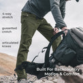 side view of man wearing green lightweight mountain pants on a peak while picking up a backpack