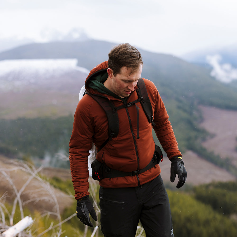 front view of hiker on top of mountain wearing red synthetic zippered jacket for backpacking