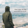 A person wearing an olive green hooded jacket stands with their back to the camera, looking out over a hazy mountain landscape. Text on the right reads 'One Layer All Day' and 'comfortable from 25-50F'.