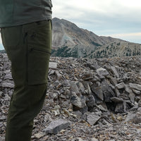 side view of men's green hiking pants on rocky mountain peak