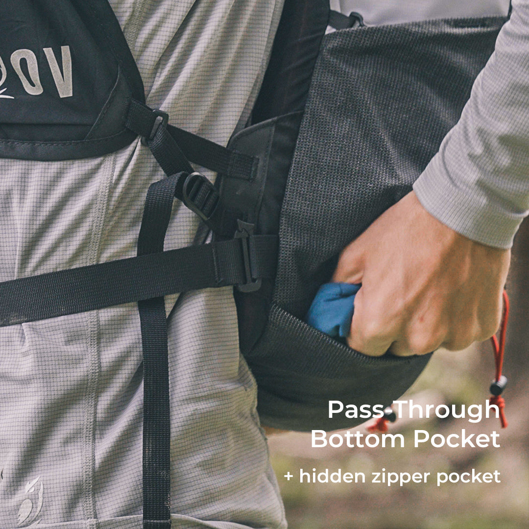 close view of hiker retrieving gear form pass-through bottom pocket beneath his fastpack. Text also describes a hidden zipper pocket within the pass-through pocket.