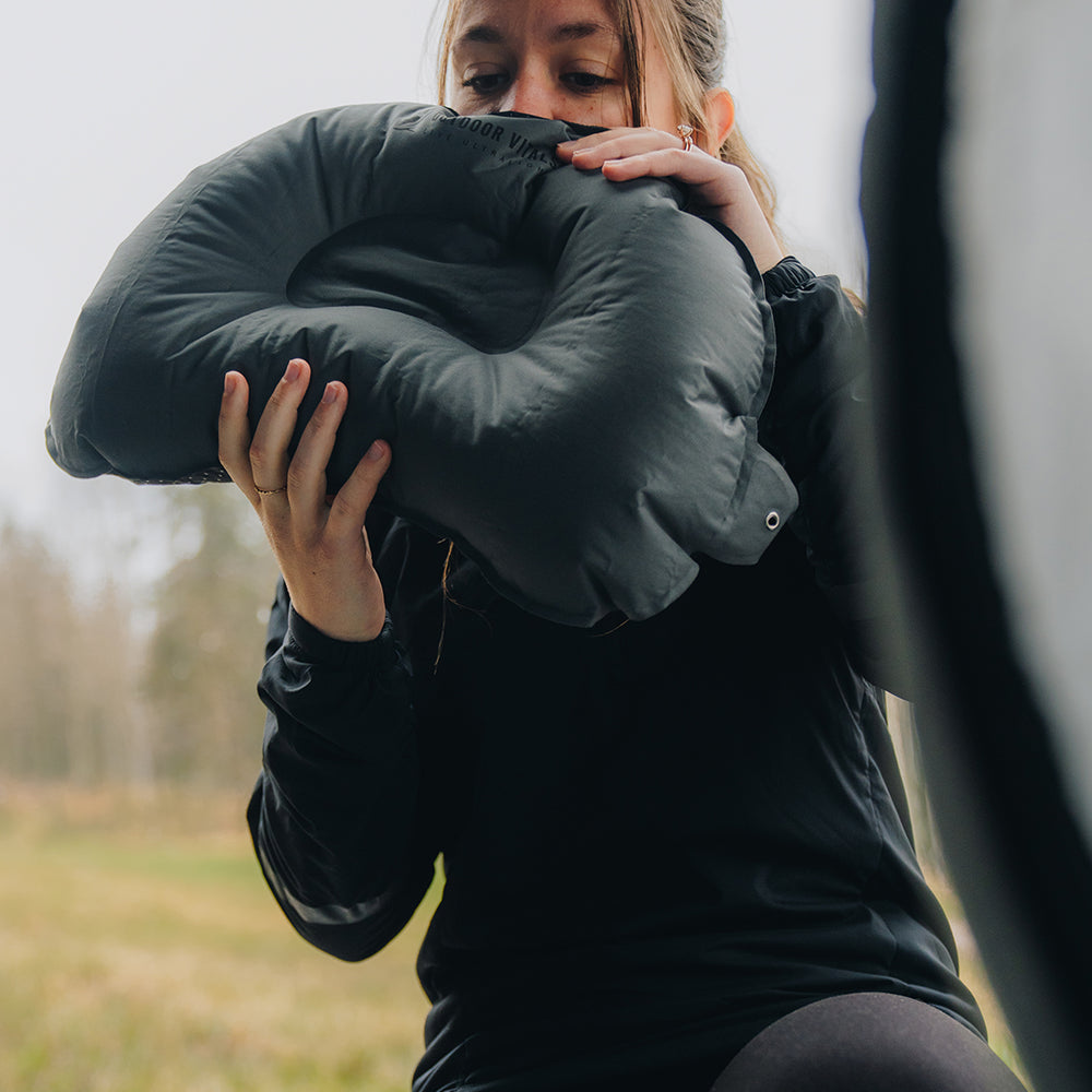 Woman inflating the Outdoor Vitals ultralight backpacking pillow inside a tent.