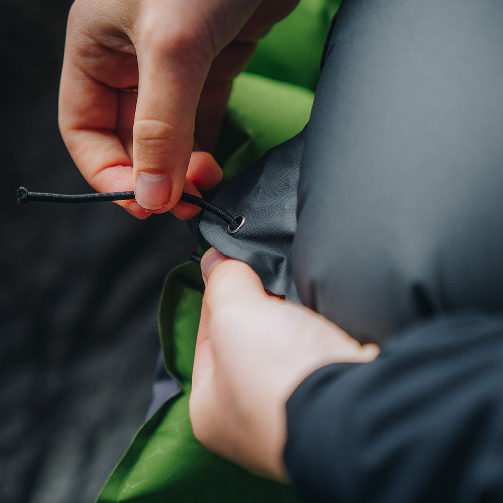 Close-up of hands attaching the ultralight inflatable pillow to a sleeping pad using the built-in strap system.