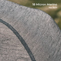 Close-up of a fine knit fabric texture in a gray and off-white merino weave, with a dark gray seam and white text reading '18 Micron Merino no itch' in the top right.