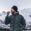 man brushing teeth at high elevation camp while wearing warm puffy down jacket.