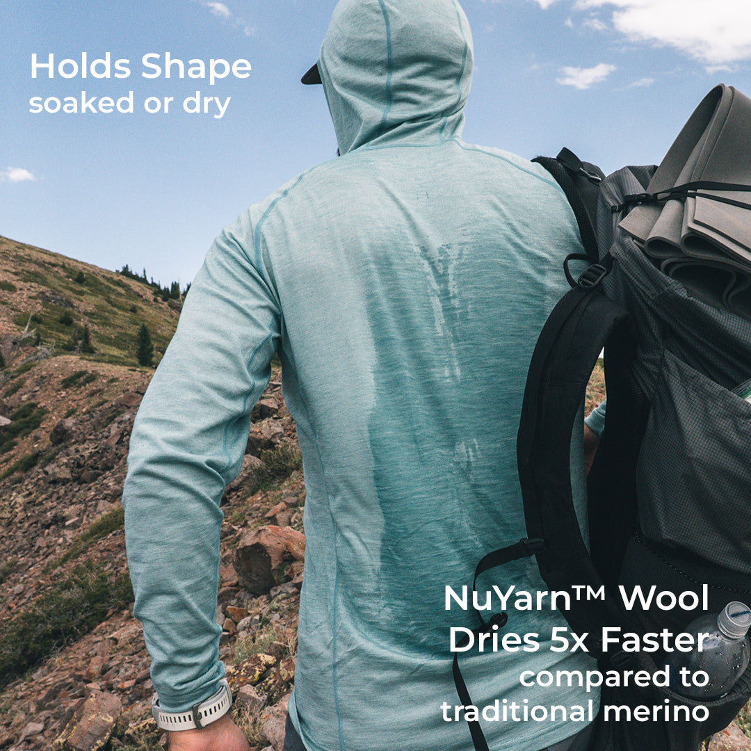 A man wearing a light blue long-sleeve hooded shirt is shown from behind in an outdoor mountain setting, carrying a black backpack. Text overlays highlight the shirt's shape-holding and drying performance using NuYarn Wool.