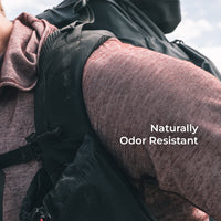 Close-up of a person wearing a backpack and a wool long-sleeve top, with the text 'Naturally Odor Resistant' overlaid on the right side.